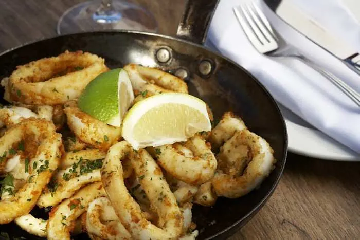 Calamari rings pan-fried in garlic and lemon butter, served in the pan with lemon wedges