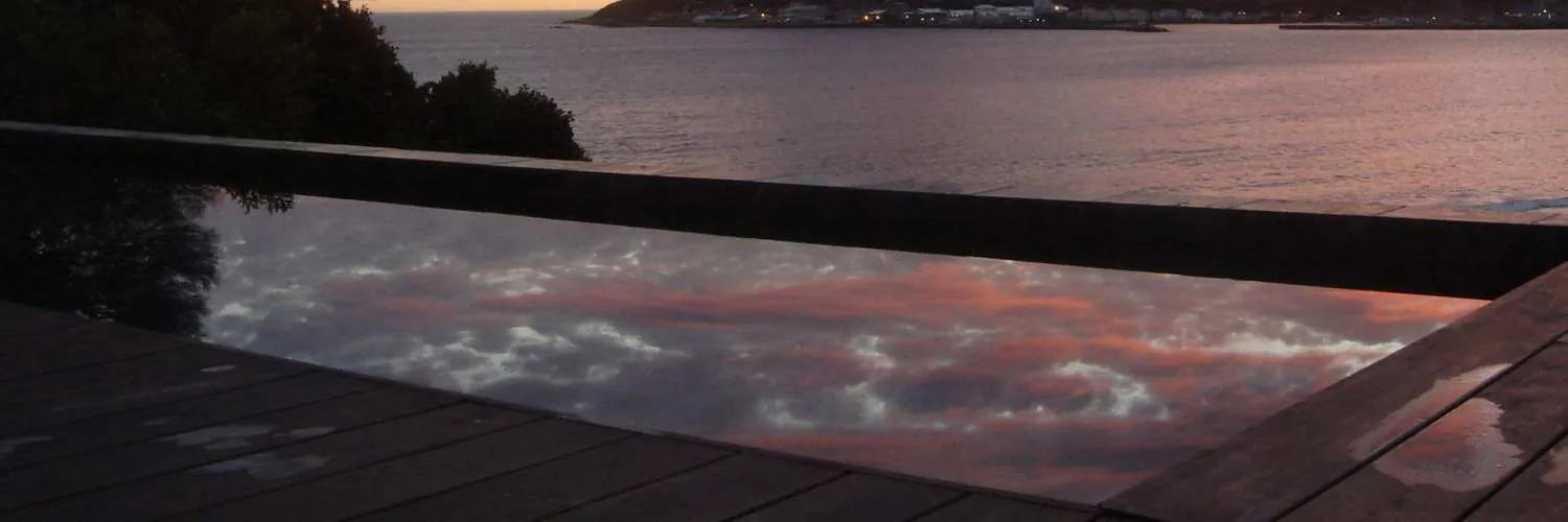 The pool reflecting a pink dusk sky over the bay