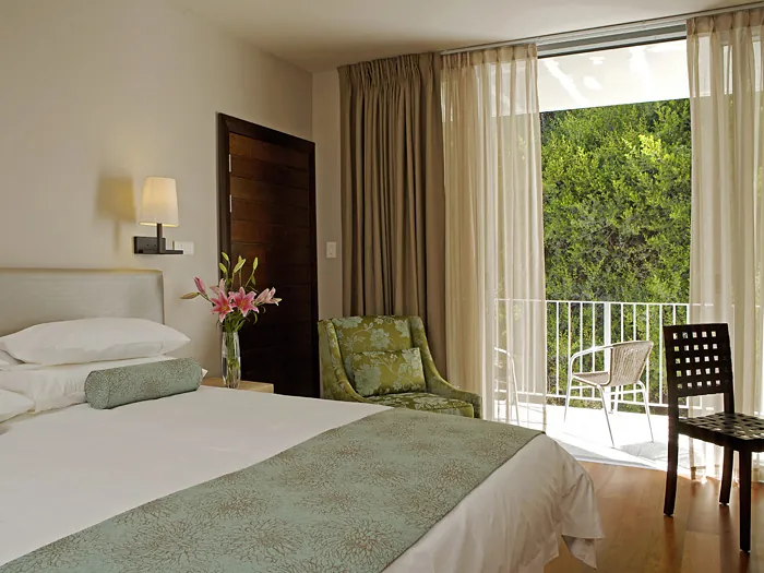 Mountain View Room with crisp linen and a balcony door open to green forest