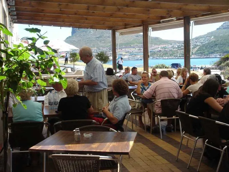Guests at lunch on the covered terrace, the bay and the Sentinel behind them